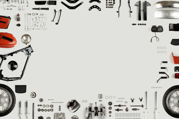 frame lined with parts of a disassembled motorcycle on a light background
