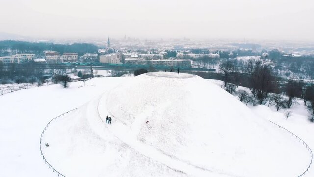 Panoramic footage covering the whole area surrounding Kopiec krakusa (Krak Mound) covered with snow in Krakow, Poland. Group of Moutaineers moving to reach the top of the mound. Light snow fall.