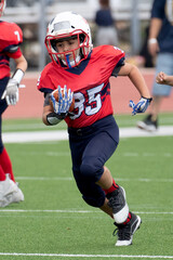 Young athletic boy playing in a youth tackle football game