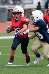 Young athletic boy playing in a youth tackle football game