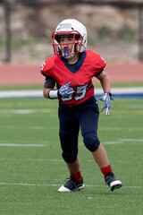Young athletic boy playing in a youth tackle football game