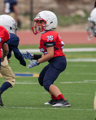 Young athletic boy playing in a youth tackle football game
