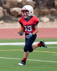 Young athletic boy playing in a youth tackle football game