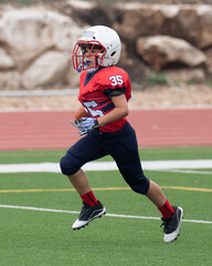 Young athletic boy playing in a youth tackle football game