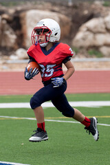 Young athletic boy playing in a youth tackle football game