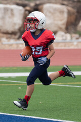 Fototapeta premium Young athletic boy playing in a youth tackle football game