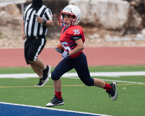 Young athletic boy playing in a youth tackle football game