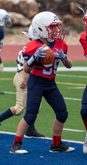 Young athletic boy playing in a youth tackle football game