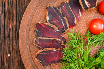 Close up of assorted sliced dry-cured meat on the wooden plate background