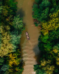Boat on Tisza river in Hungary surrounded by green trees. Aeriel view.