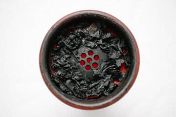 Red silicone hookah bowl with burnt fruit tobacco after smoking. Close-up. On a white background. View from above.