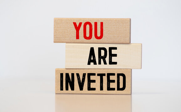paper with text YOU ARE INVETED. on wooden block