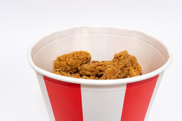 Deep fried spicy chicken wings in a crispy breading in a basket, chicken fast food isolated on white background