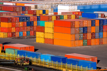 Fototapeta premium container terminal port warehouse with export cargo stockpiled and transported by truck with trailer stacks of multi-colored iron containers brokerage services, nobody.