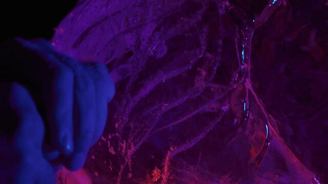 Close up of the hands of an artist using a chisel to make the mane of ice lion
