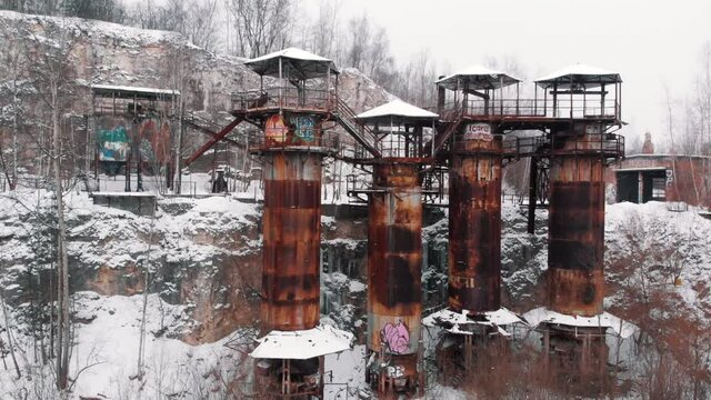 Front view of of Liban Quarry - A historic site where prisoners were kept during Second World War. Old machines and piping equipment. Light snow-fall. Snow-covered trees in the background. 