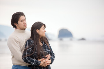 Young man holding girfriend from behind looking out towards ocean