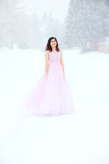 Fototapeta na wymiar Teen girl in pink formal dress on snowy day outdoors