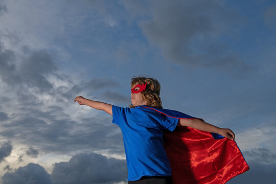 Superhero kid against blue sky background. Copy space.