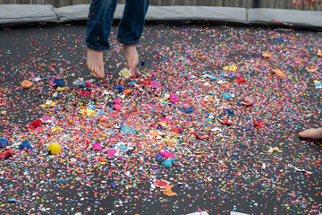 Child bouncing on trampolene covered in egg shells and confetti