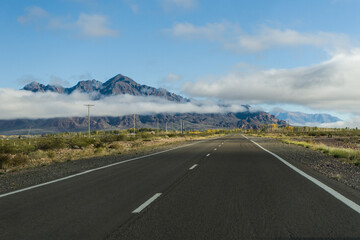 Empty road or route with mountains covered by clouds in the background