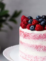 Cake decorated with raspberries and blueberries. Background in a blur