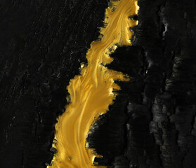 Vivid contrast of black and gold in abstract background of metallic gold paint swirling over...