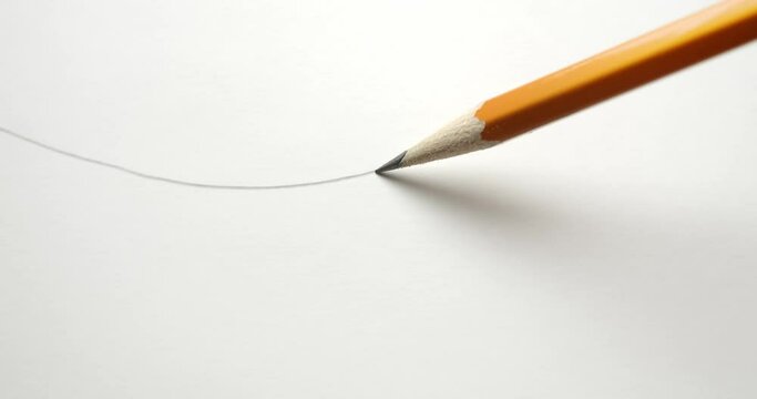 Drawing a wavy line across paper with a yellow pencil.