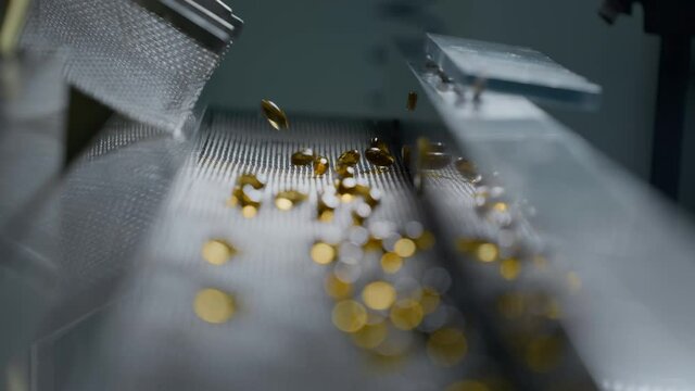 Gelatin capsules in the production of vitamins and medicines. Supplements are made on an automatic machine or medical conveyor equipment. Pharmacological plant of amber-colored drugs. Slow motion