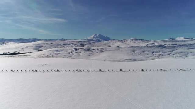 Flying along the snowy foot of the mountain on a sunny day