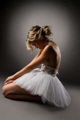 Topless ballerina kneeling on floor during dance - obrazy, fototapety, plakaty