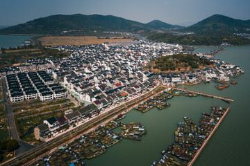 Aerial of a Chinese old fishing village, with rows of traditional houses and fishing boats in the harbor