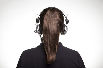 Closeup of Brazilian female wearing a headphone around her ponytailed hair on a white background