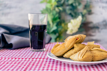 Tamales served on a traditional table with a glass of red wine. A typical sandwich or Latin American meal of cornmeal and meat. Traditional Andean food. Traditional food concept