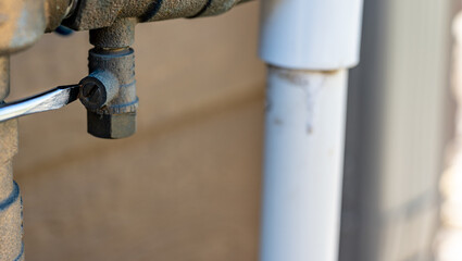 Preparing to start up a sprinkler irrigation system in the spring by closing the test cocks and opening the valves next to the vacuum breaker.