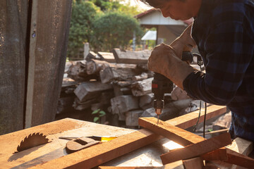 Carpenter drills a hole with an electrical drill Carpenter doing his job in carpentry workshop.