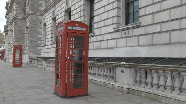 Red telephone booths beside an old building in London.