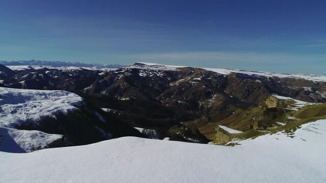 Flying along a mountain snowy cliff