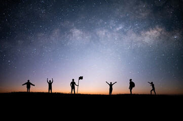 Silhouette group of tourists and looking view of star and milky way on the top of the mountain and raise their hands pointing to the stars before sunrise. We are happy to be with herself and nature.