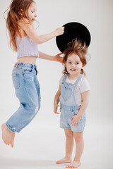 Cute little girls play with a black hat. the child tries on mothers clothes.