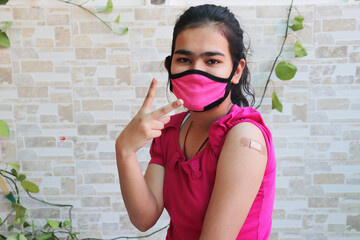 Indian girl wearing mask do victory Sign after getting vaccination during new strain of covid-19,...