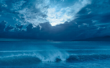 Moon rising over empty ocean at night, power sea wave in the foreground 