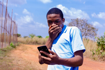 an handsome african boy got surprise about the new he saw on his cellphone