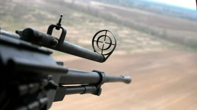 12.7 mm machine gun with a round front sight is aimed at forest objects in a copter  
