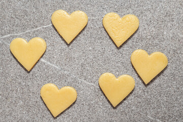 Heart cut cookies from dough on a gray table background. Raw biscuits prepared for baking homemade biscuits