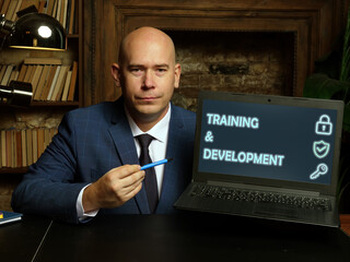  TRAINING & DEVELOPMENT text in search bar. Businessman looking for something at laptop. TRAINING & DEVELOPMENT concept.
