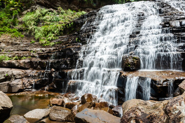 Obraz premium Mayagusuku waterfall in the middle of the jungle on the island of Iriomote with its formation in stones ladder and its waters flowing over them.