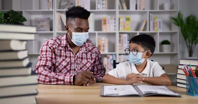 Young african teaching asian boy during quarantine at home