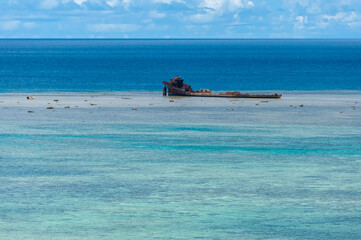 Closeup of a shipwreck surrounded by a beautiful blue gradient sea full of corals. Transport ship,...