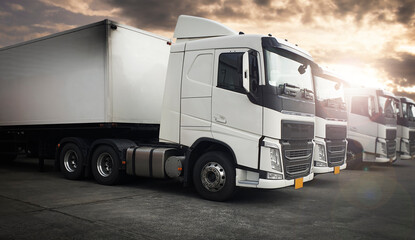 Fototapeta na wymiar White Modern Semi Truck In A Row The Parking Lot At Sunset Sky. Cargo Freight Truck Transportation.